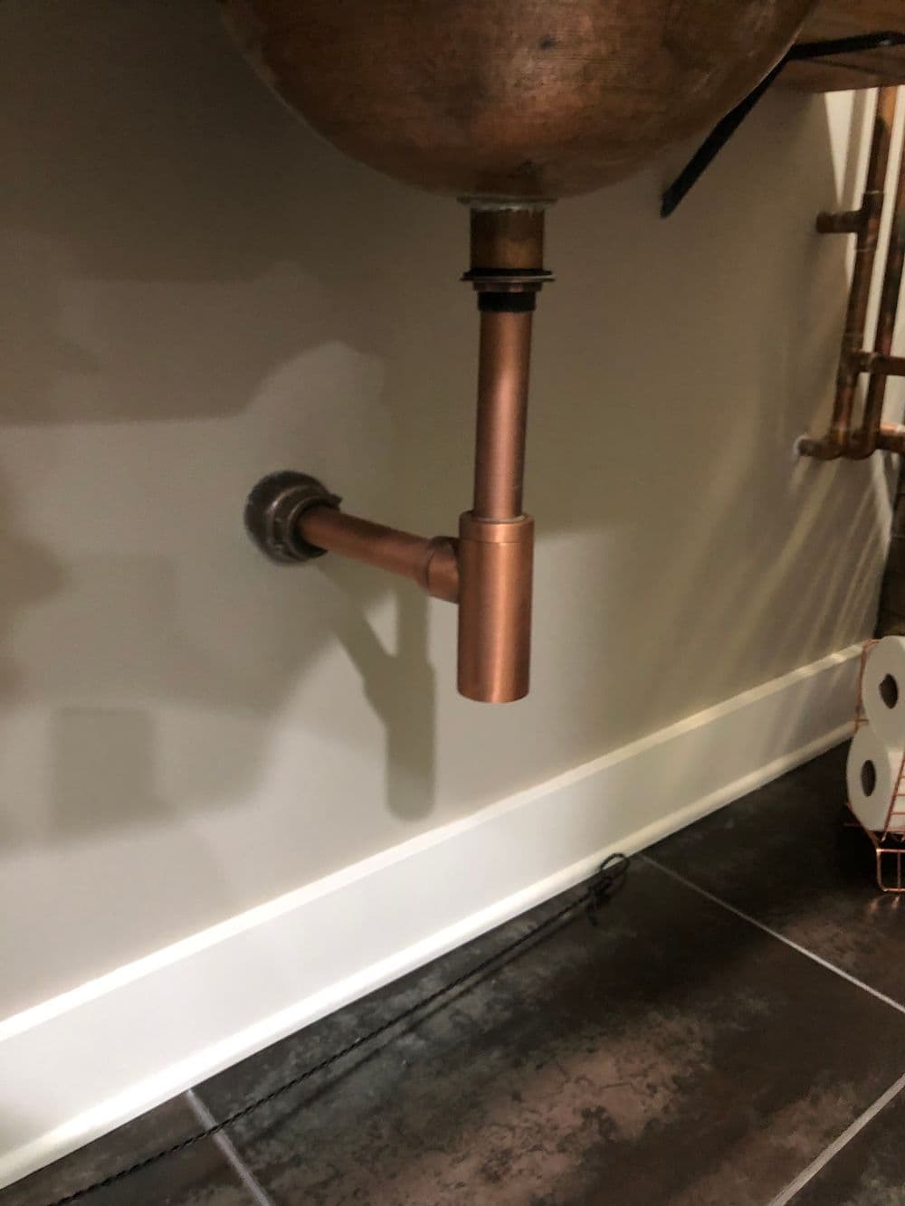 Copper plumbing pipe under a sink, showcasing modern home plumbing design.