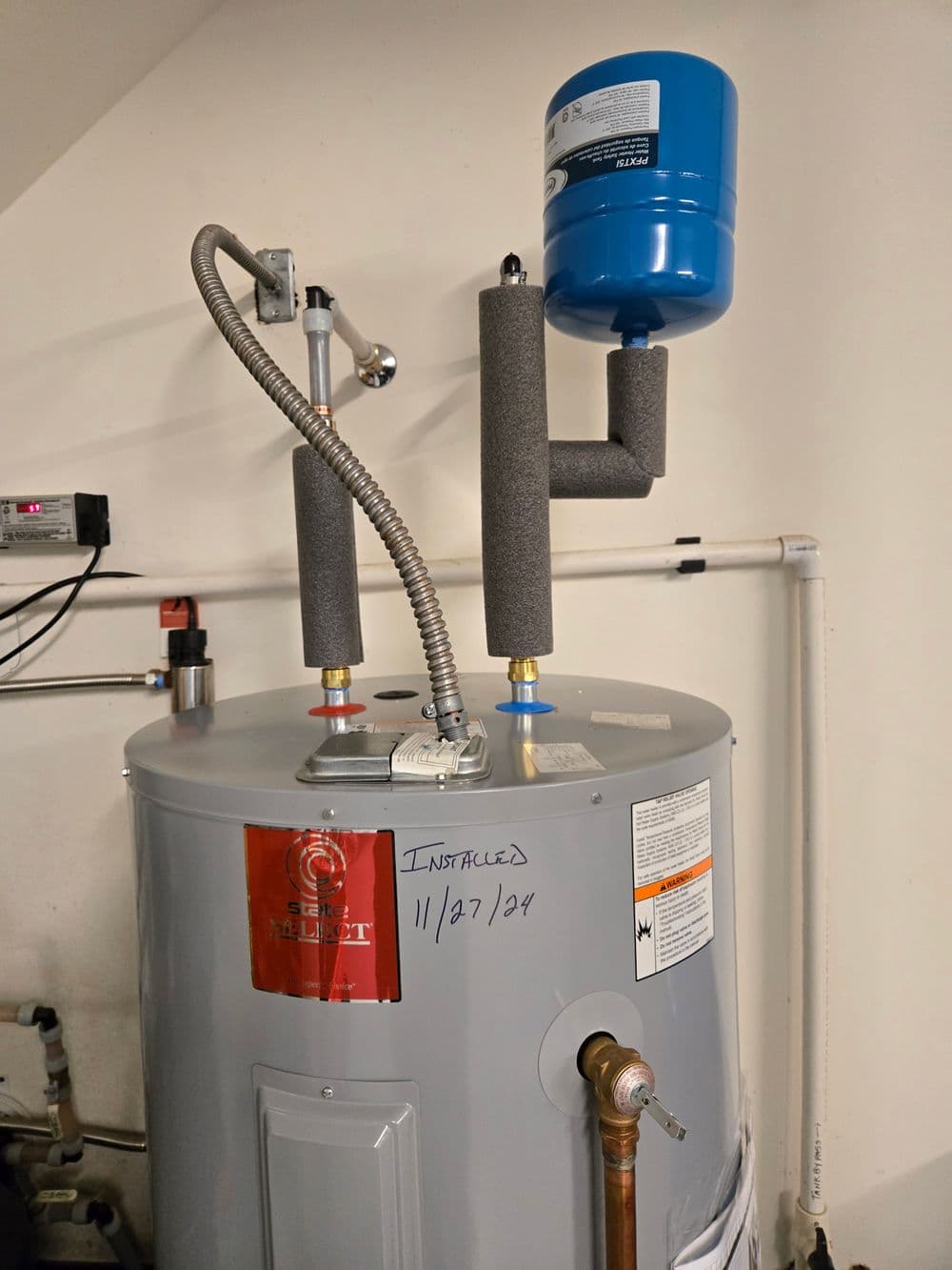 Water heater with insulation, expansion tank, and installation date marked on the side.