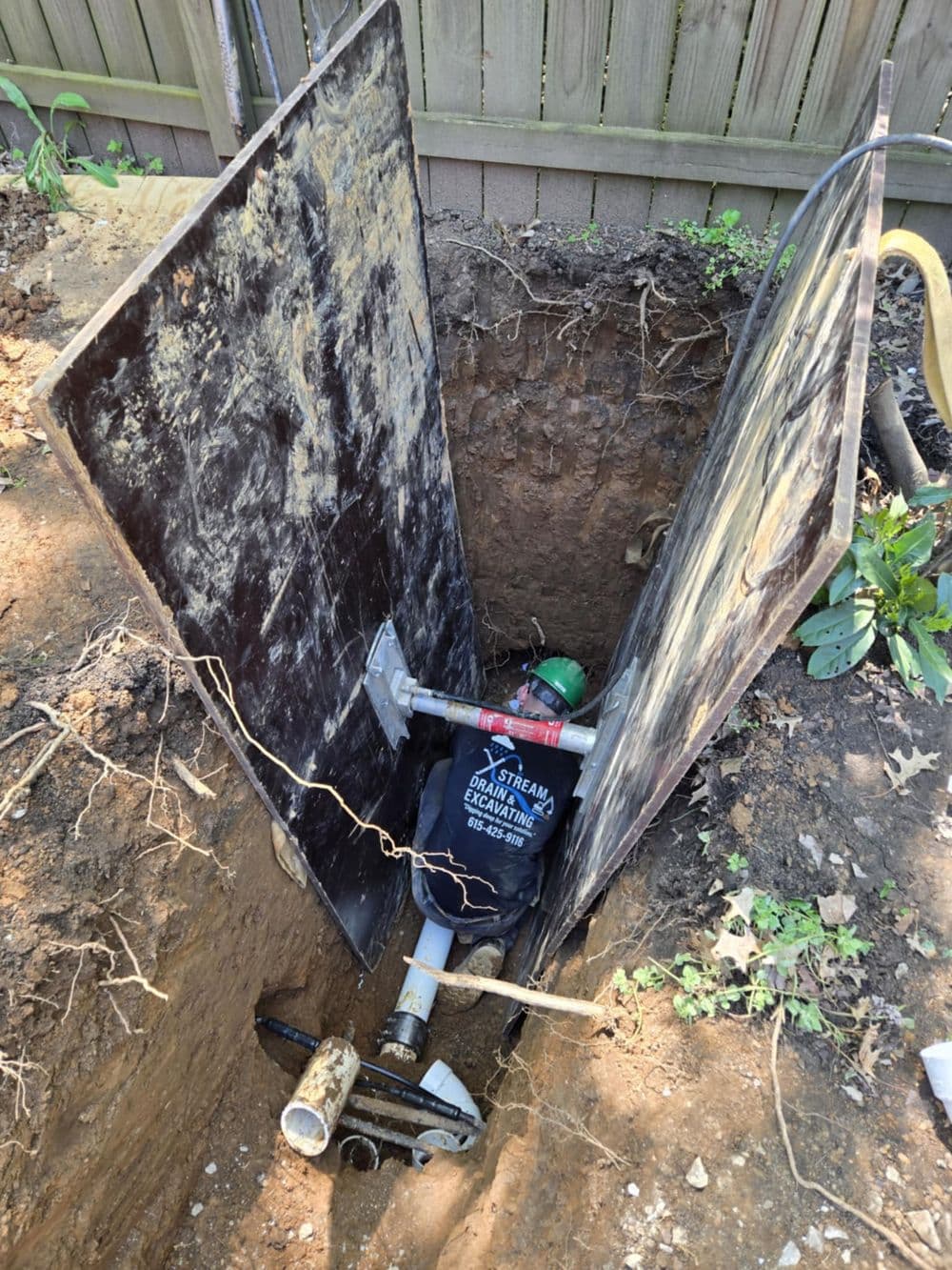 Excavation site with a sump pump and protective cover in a yard.