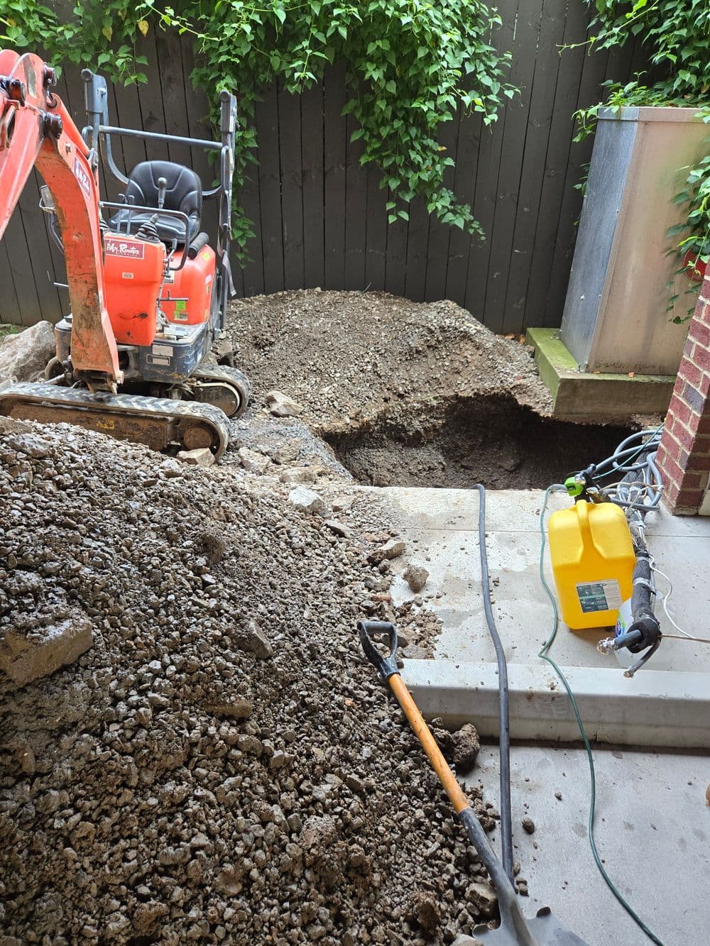Excavation site with machinery and dirt piles in a backyard, preparing for landscaping project.