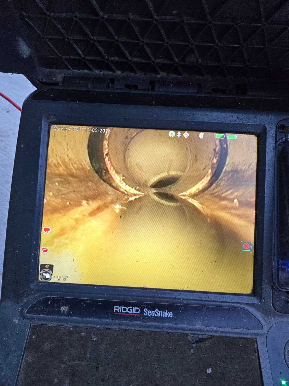 Video inspection screen showing sewer pipe interior with debris on the walls.