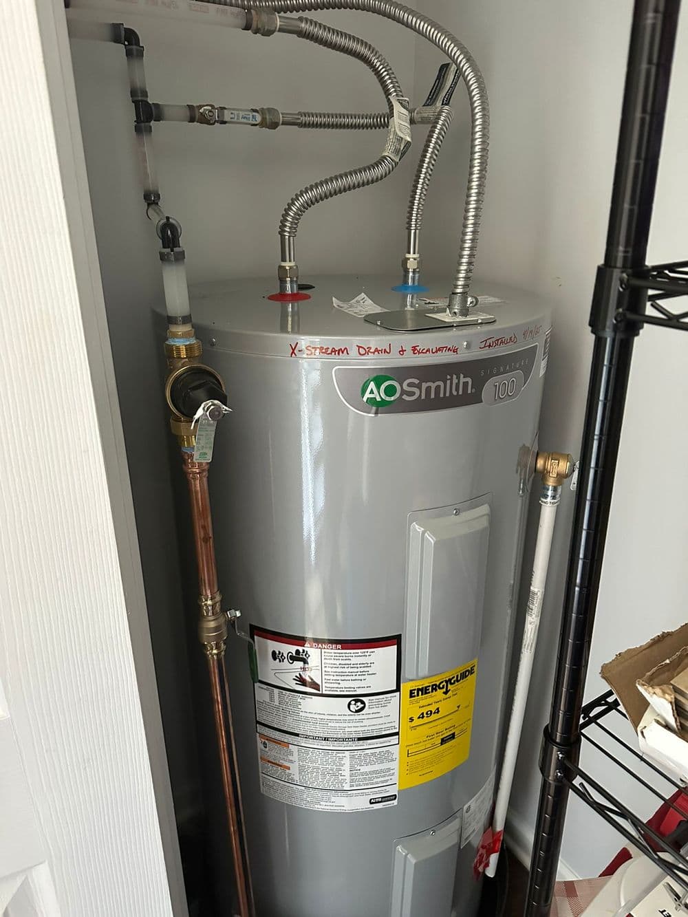 AO Smith water heater with energy efficiency label in a utility closet setting.