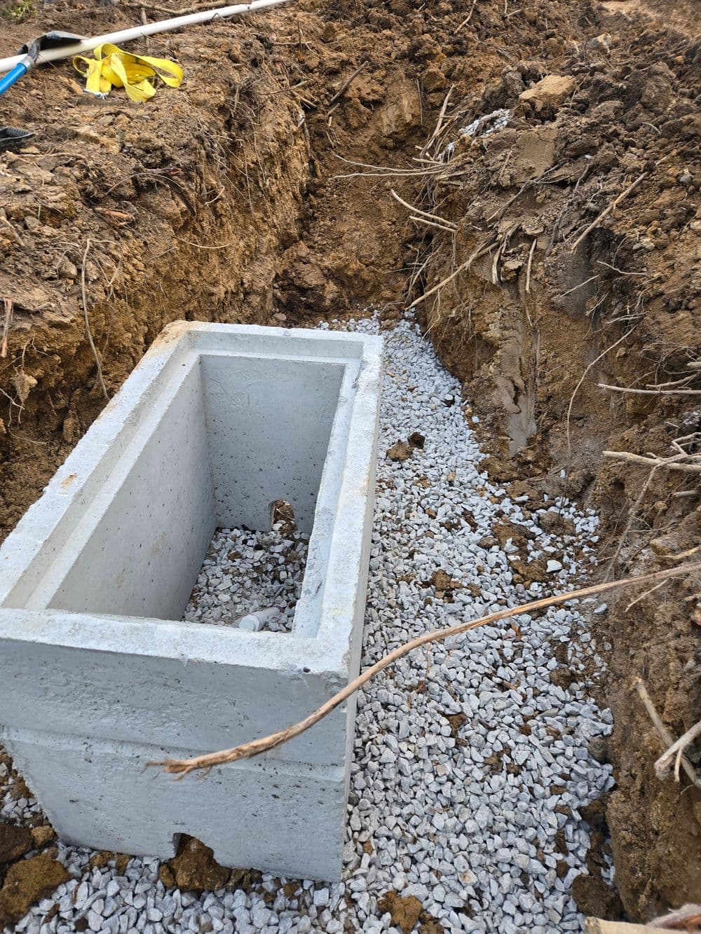 Excavated trench with a concrete block and gravel, ready for construction work.