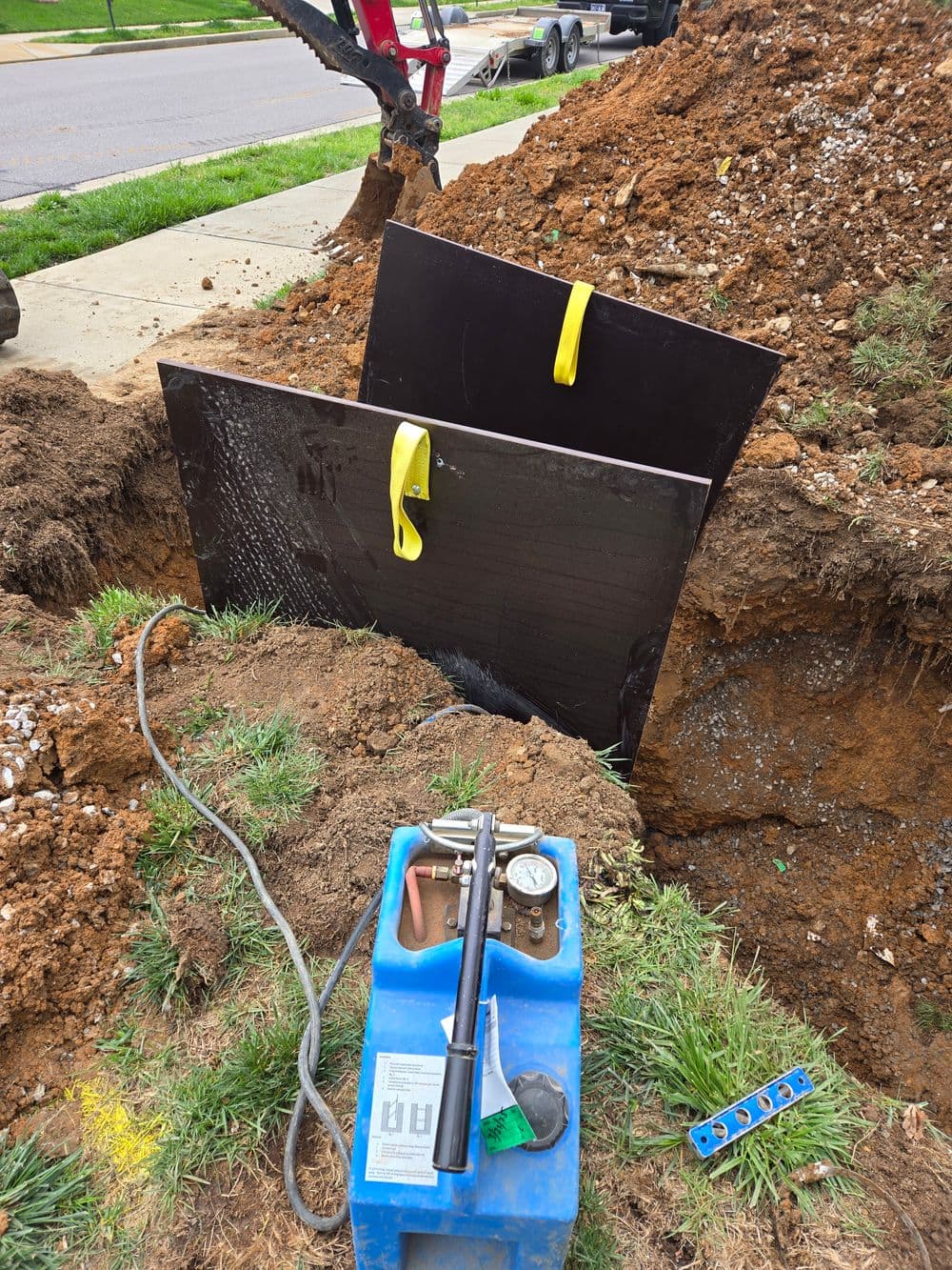 Black construction panels on a dirt mound at a worksite with construction tools nearby.